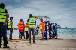 The photo shows a number of people launching a boat.